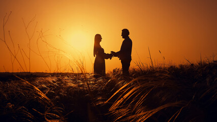 Sunset landscape with two lovers, a man and a woman. Beautiful nature in summer. Natural spikelets...