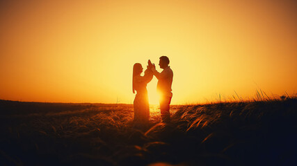 Sunset landscape with two lovers, a man and a woman. Beautiful nature in summer. Natural spikelets of grass developing in the wind.