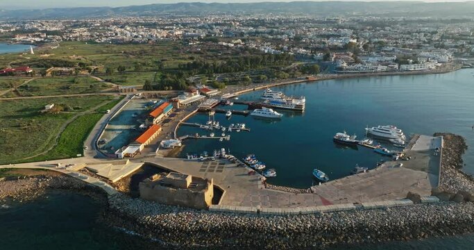 Aerial view of the port and marina in Pathos, Cyprus. A tourist place with an old castle near which there are locos and yachts on the pier in the cityscape of the Mediterranean Sea. High quality 4k 