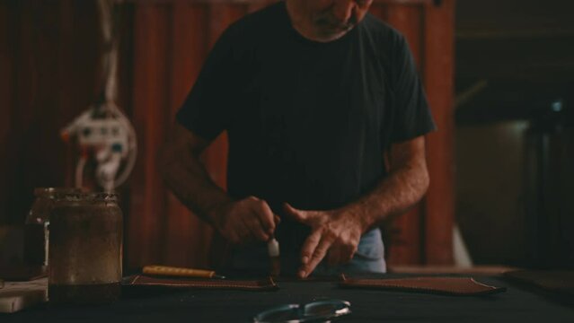 Leather craftsman dips and dabs paste onto leather