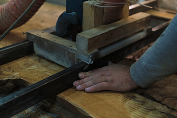 A skilled craftsman operates a bandsaw, precisely cutting a wood slab. Precision and safety are paramount in his work.