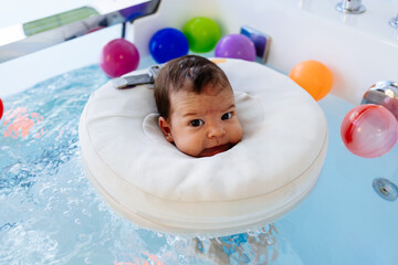 Small child or a baby is swimming and having a pleasant time during a physical therapy session in the pool.