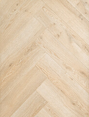 Geringbone pattern laminate in light brown with shades of beige, imitating the texture of natural...