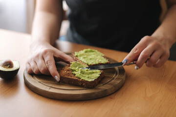 Woman are spreading guacamole on toasted dark bread