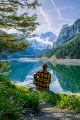 A man enjoys the wonderful atmosphere of the morning, next to a lake surrounded by alpine mountains.