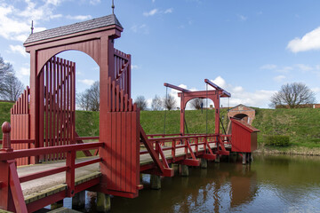 View of canal with bright red bridge and rampart around the village of Bourtange (former Fort...
