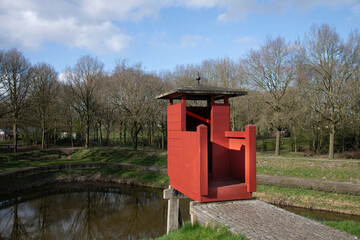 Red wooden guardhouse on the rampart of the village of Bourtange (former Fort Bourtange), near Westerwolde the Netherlands; the fortress was built in 1593 shape of a star  - obrazy, fototapety, plakaty