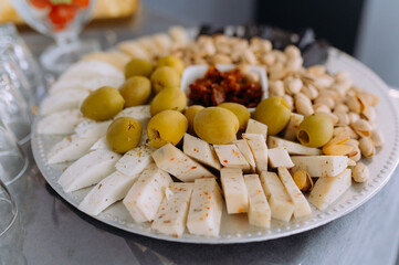 close-up view of a plate with cheese, pistachios, olives. sliced cheese with olives and nuts