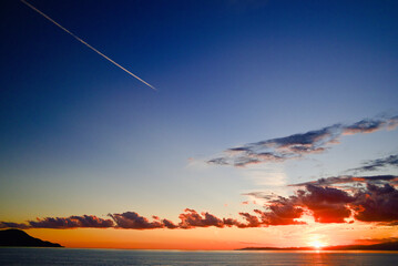 夕焼けの海と飛行機雲