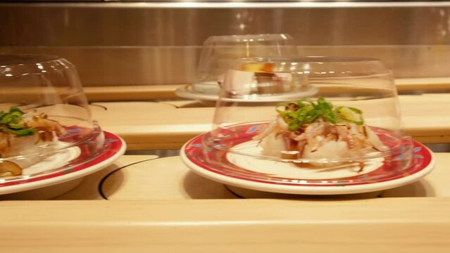 Sushi dishes riding on a conveyor belt at a Japanese restaurant.