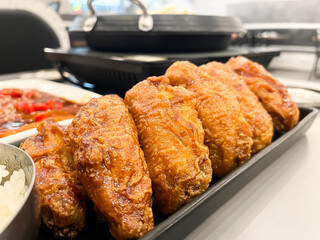 Close-up of crispy golden fried chicken wings served on a black rectangular plate. Deliciously glazed and perfectly cooked, these wings are ideal for fast food menus