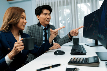 Successful of smiling Asian businesswoman holding cup while pointing to dynamic stock exchange data...
