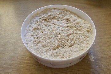 a container with a raw yeast dough on the wooden kitchen table.