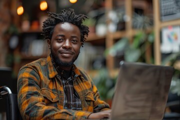 Obraz premium A young man in casual attire works on a laptop amid lush greenery in a bright greenhouse environment
