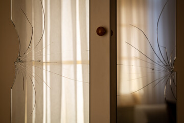 Broken mirrors on the wardrobe door. Reflection of the window and tulle curtain in the mirror.