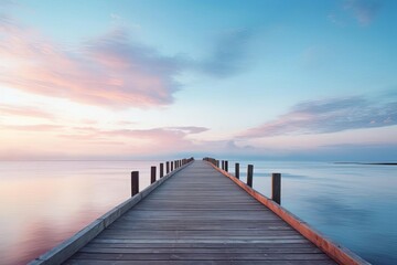 A serene coastal scene with a single wooden pier extending into a calm ocean at dawn, space for text