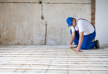 man worker takes measurements during the installation of a warm floor