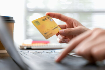 Woman hand holding a credit card and using laptop to pay online. The concept of online shopping and...