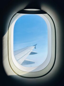 View of an airplane wing through an aircraft window in flight