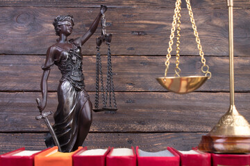 Law concept - Open law book, scales, Themis statue on table in a courtroom or law enforcement office.