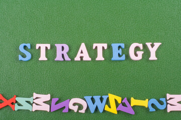 STRATEGY word on green background composed from colorful abc alphabet block wooden letters, copy...
