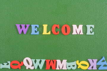 WELCOME word on green background composed from colorful abc alphabet block wooden letters, copy...