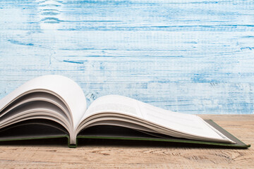 Composition with hardback books, fanned pages on wooden deck table and blue background. Books stacking. Back to school. Copy Space. Education background.
