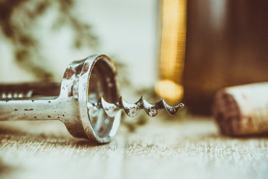 Close-up of a metal corkscrew with bottle opener next to a cork on a table
