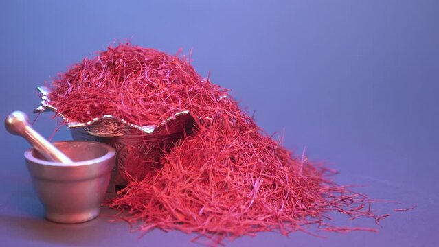 Saffron threads in a silver bowl beside the mortar