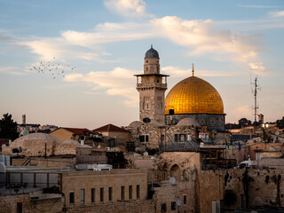 Birds flying around the dome of the Rock at sunset