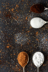 Spoons with icing sugar, green tea, coffee and cocoa on black background sprinkled with sugar,...