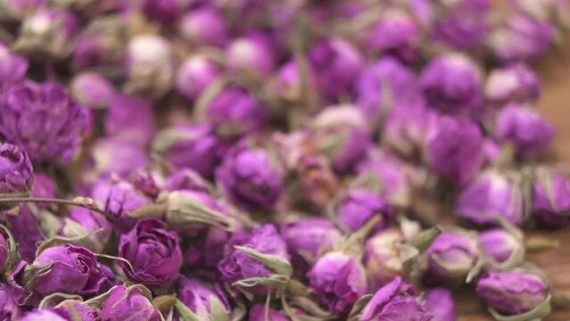 Close up view of small wooden bowl surrounded by damask rose buds with soft focus