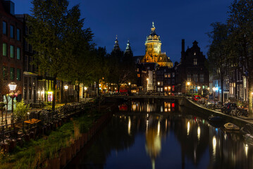 The Basilica of Saint Nicholas in Amsterdam reflecting in the waters of the Voorburgwal canal  at...