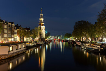 The Montelbaanstoren tower in Amsterdam reflecting in the waters of the Oudenschans canal at night