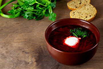 red beet soup. delicious borscht with sour cream, garlic, green parsley. Traditional Russian and Ukrainian dish on a wooden background. copy space.