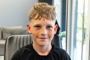 A picture of a very happy child after being cut in a barbshop salon, he has a very nice cut and has...