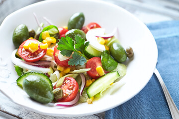 Simple Salad with Green Olives, Cucumber and Cherry Tomatoes. Bright wooden background.	