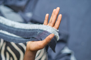 A hand holding shredded raw denim fabric in a denim factory. Industrial fabric and fashion...