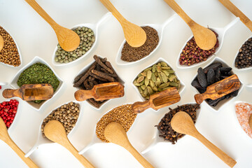 Fine spices from all over the world in bowls with small wooden spoons