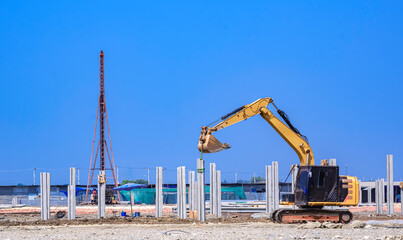 Excavator with pile driver machine are working to installing many precast concrete piles for...