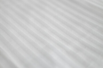 Elegant textile on bed. Striped pattern on a snow-white bedsheet. The manufacturing of bedsheet...