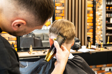 Funny preschooler boy getting haircut. Children hairdresser with the trimmer is cutting little boy...