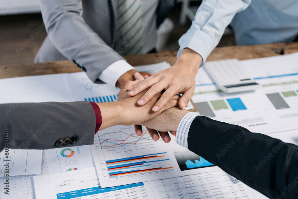 Poster A group of people are shaking hands on a table with a lot of graphs and charts