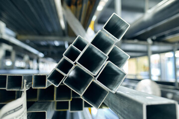 Metal steel square piping pipes stacked up on an industrial heavy duty racking in an industrial...