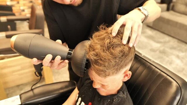Video in the barbershop with a freckled and blond child with very beautiful hair with a desire to have curly hair, and for this solution is a hair diffuser.