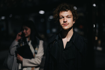 Obraz premium A focused young male entrepreneur with a confident look while his business partner is on the phone in the blurred background.