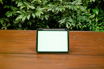 Blur Green Screen iPad or Tablet on Wooden Table with Green Plants Background
