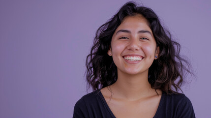 Fototapeta premium A woman with curly hair is smiling and looking at the camera
