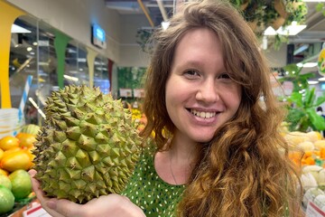 girl buys tropical fruit durian with a pungent smell in the supermarket