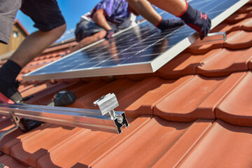 Dachdecker beim Aufbau einer Photovoltaikanlage auf einem neu gedeckten Ziegeldach: Die Endklemmen...